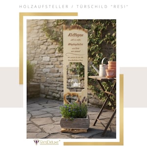 Könnte beinhalten: Ein Holzschild mit dem Text "HOLZAUFSTELLER / TÜRRSCHILD 'RESI'" und einem dekorativen goldenen Rahmen. Das Schild hat einen Pflanzkasten an der Basis mit Lavendel und einem herzförmigen Ausschnitt. Ein Glaskerzenhalter hängt am Schild.