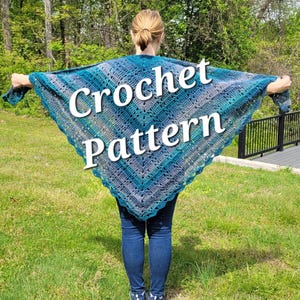 May include: A person wearing a blue, teal, and gray crochet shawl with the words "Crochet Pattern" overlaid on the image. The shawl has a triangular shape and a scalloped edge. The person is wearing blue jeans and white sneakers.