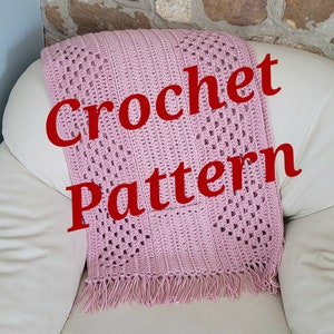 May include: A pink crochet blanket with a fringe border. The blanket is on a white couch and the words "Crochet Pattern" are written in red on top of the blanket.