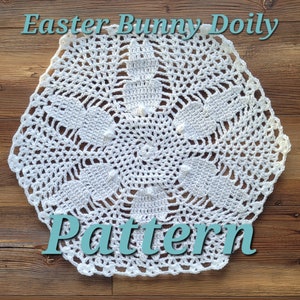 May include: White crochet doily with a delicate floral pattern. The doily is shaped like a hexagon and has a center design that resembles a bunny. The text "Easter Bunny Doily Pattern" is written below the doily.