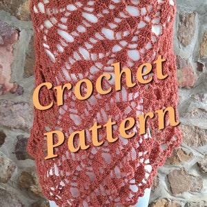 Könnte beinhalten: Ein gehäkeltes Tuch in Rostorange. Das Tuch wird auf einer Schaufensterpuppe vor einer Steinwand präsentiert. Der Text "Crochet Pattern" ist über das Bild gelegt.