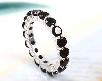 May include: A silver band ring with a full eternity row of black gemstones.