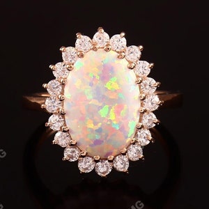 May include: A gold ring with a large oval opal surrounded by a halo of smaller diamonds.