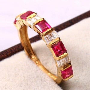 Könnte beinhalten: Ein Goldring mit abwechselnden roten Rubin- und klaren Diamantensteinen.