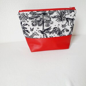 Puede incluir: Una bolsa de cremallera roja y blanca con un estampado de jungla en blanco y negro. El estampado presenta palmeras, una jirafa, un loro y un mono.