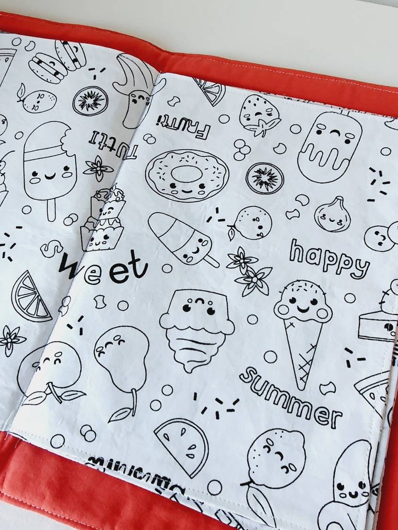 Puede incluir: Libro para colorear abierto con un interior blanco que presenta dibujos lineales negros de frutas, postres y las palabras "sweet", "happy" y "summer". El libro est&aacute; encuadernado con un borde rojo.