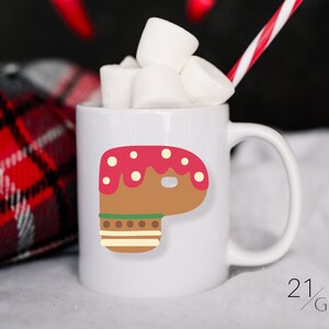 Può includere: Tazza in ceramica bianca con un design a forma di pan di zenzero. L'uomo di pan di zenzero è marrone con glassa rossa e codette bianche. La tazza è piena di marshmallow.