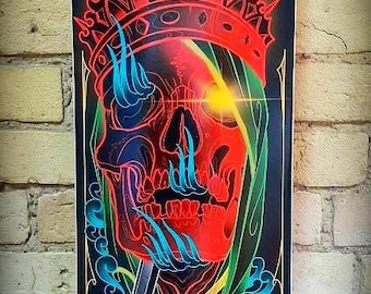 May include: A black skateboard deck with a colourful graphic design. The design features a skull wearing a crown, a sword, and a rope. The text "Suicide King" is written in gold lettering at the bottom of the deck.