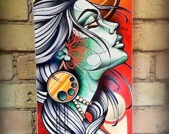 May include: A skateboard deck with a colorful illustration of a woman with long flowing hair, a castle in the background, and a crescent moon with a swirling pattern. The woman has a green face and is wearing a gold necklace and earrings.