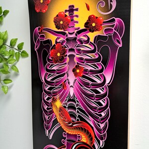 May include: A black and purple ribcage with a red snake wrapped around it. Pink flowers are falling from the top of the image.