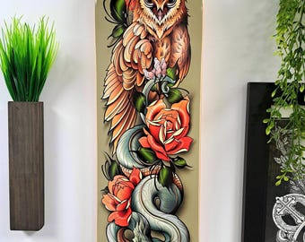 May include: A green skateboard deck with a colorful illustration of an owl, a snake, and roses. The owl has orange eyes and is perched on a branch with its wings spread. The snake is wrapped around the branch and has a green and blue color scheme. The roses are red and have green leaves.