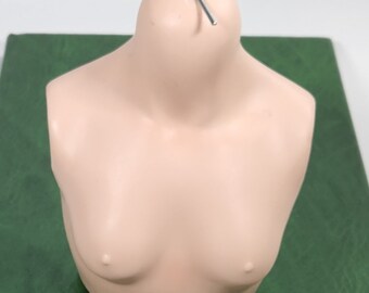 May include: A light pink mannequin torso with a wire inserted into the top of the neck.