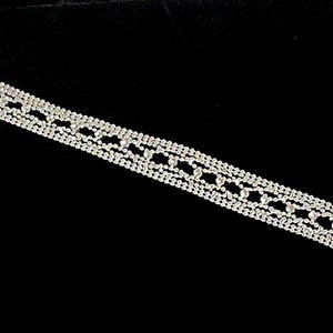 Puede incluir: Un brazalete plateado con un diseño delicado y multicapa. El brazalete está hecho de pequeñas cuentas enlazadas y tiene un cierre de broche.