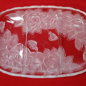 Puede incluir: Un plato de servir de vidrio transparente con tres secciones. El plato está decorado con un diseño grabado de rosas y hojas.