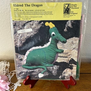 May include: A green felt Eldred the Dragon sewing kit from Needle-In-The-Haystack. The kit includes pre-cut pieces and instructions for making a 17-inch plush dragon. The kit also includes iron-on eyes and a wool and rayon felt nose.