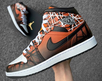 May include: High-top orange, black, and white sneakers with a geometric pattern. The sneakers feature a black Nike swoosh and white laces. The Air Jordan logo is visible on the side. A second sneaker and box are in the background.
