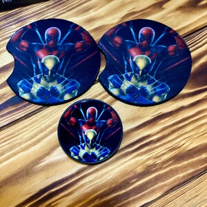 Puede incluir: Dos posavasos redondos negros y rojos con un gr&aacute;fico de Deadpool y Wolverine. Tambi&eacute;n se muestra un posavasos redondo m&aacute;s peque&ntilde;o con el mismo gr&aacute;fico.
