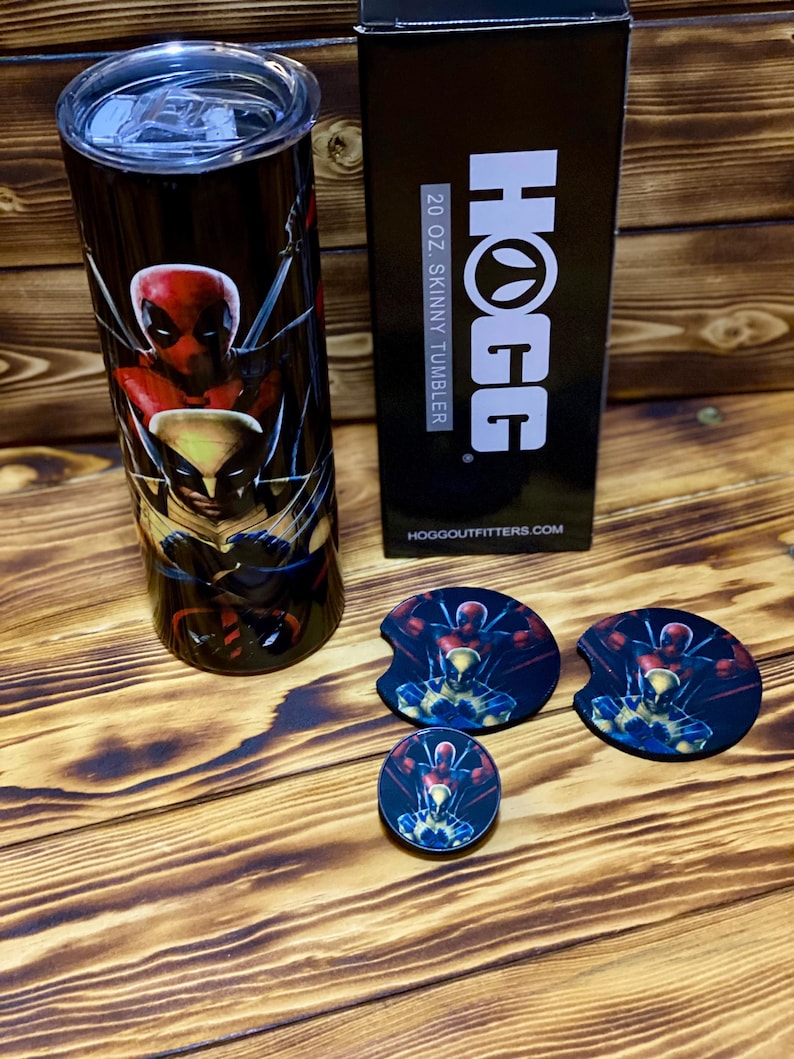 Puede incluir: Un vaso delgado de acero inoxidable de 591 ml con un gr&aacute;fico negro y rojo de Deadpool y Wolverine. El vaso est&aacute; al lado de una caja con el texto "HOGG 20 OZ. SKINNY TUMBLER" y una direcci&oacute;n de sitio web. Hay tres posavasos con el mismo gr&aacute;fico que el vaso.