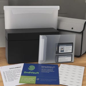 May include: A collection of storage containers and documents. Includes a clear plastic bin, a black box, a gray fabric case, and a clear plastic file holder with cards. Several documents are visible, including one with the text "2ndVault".