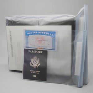 May include: Clear plastic document organizer with a Social Security card and a United States passport visible. The organizer is partially filled with white documents and has a document checklist printed on the side.