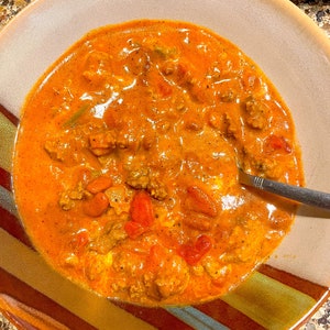 Peut inclure: Un bol de chili avec du b&oelig;uf hach&eacute;, des haricots et des tomates. Le chili est d'une couleur rouge fonc&eacute; et est surmont&eacute; d'une cuiller&eacute;e de cr&egrave;me fra&icirc;che.