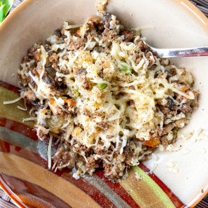 Peut inclure: Un gros plan d'un bol de b&oelig;uf hach&eacute; au fromage, de riz, de champignons et de petits pois. Le bol a un motif ray&eacute; brun et blanc.