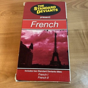 Può includere: Una custodia per VHS rossa e bianca con il titolo "The Standard Deviants present: French" e un'immagine della Torre Eiffel. La custodia include due titoli: "French I" e "French II".