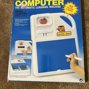 Könnte beinhalten: Eine Vintage Smart X Educational Computer Box. Die Box ist blau und weiß, mit den Worten "Educational Computer" in großen gelben Buchstaben. Sie enthält 42 Karteikarten, Rechtschreib- und Rechenkarten, eine Tafel und einen Radiergummi.