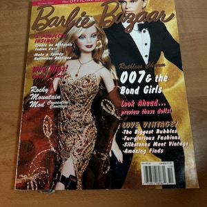 Könnte beinhalten: Ein Magazin-Cover für Barbie Bazaar, das eine Barbie-Puppe in einem goldenen Kleid und einen Mann im Smoking zeigt. Der Titeltext lautet "Ruthless Charm 007 & the Bond Girls".