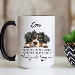 May include: A white ceramic mug with a black handle and rim, featuring a black, brown, and white illustration of a dog peeking over the text "Coco" and the phrase "Thank you for the walks, Thank you for the treats, Thank you for loving me."
