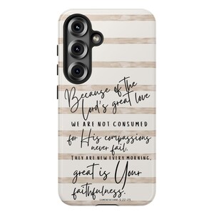 May include: A phone case with a white and beige striped background. The case features the text "Because of the Lord's great love...great is Your faithfulness." The case has a black camera module.