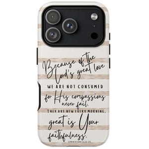 May include: A phone case with a cream and tan striped design. The case features the text "Because of the Lord's great love...great is Your faithfulness." The case has a black camera module with three lenses.