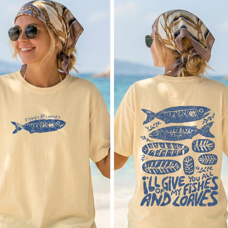 May include: Cream-colored t-shirt with a blue fish graphic and the text "Fishes and Loaves" on the front. The back of the shirt features a larger design with fish and the text "I'll give you all of my fishes and loaves".