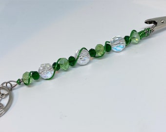 May include: A green and clear crystal beaded keychain with a silver clip and a silver key ring.