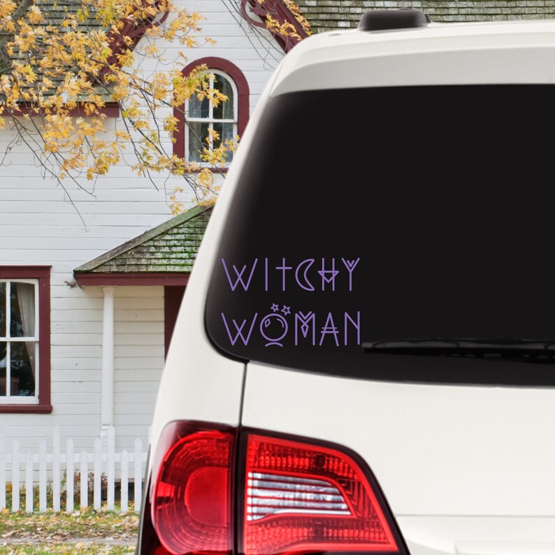 May include: A white car with a purple vinyl decal on the back window that reads "Witchy Woman" with a crescent moon and stars.