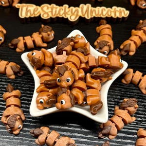 May include: A collection of brown and tan articulated horse figurines, some inside a star-shaped white dish. The figurines have dark brown manes and tails. The text "The Sticky Unicorn" is visible in the background.