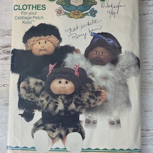 May include: Vintage Butterick sewing pattern for Cabbage Patch Kids clothes. The pattern features illustrations of three dolls wearing faux fur coats in black, white, and leopard print. The pattern includes the text "CLOTHES For your Cabbage Patch Kids!" and the number 6984.