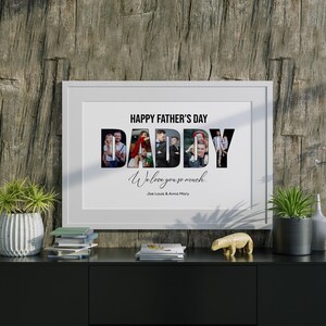 May include: A framed print with the text "HAPPY FATHER'S DAY DADDY We love you so much" and family photos inside the word "DADDY". The print is displayed on a black cabinet with decorative items and plants.