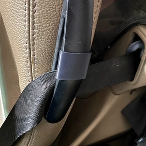 May include: A black plastic handle with a black strap attached to it. The handle is attached to a brown leather seat.