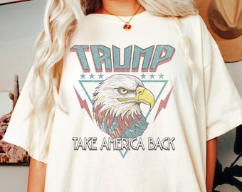 May include: A white t-shirt with a vintage-style graphic of an eagle with the text "TRUMP TAKE AMERICA BACK" printed on it.