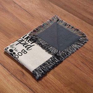 May include: A white woven throw blanket with black text that reads "I like big dogs and I cannot lie". The blanket has a fringe border and is folded in half. The back side of the blanket is a dark gray color.