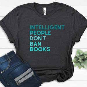 May include: A dark heather grey t-shirt with the text "INTELLIGENT PEOPLE DON'T BAN BOOKS" in teal blue lettering.