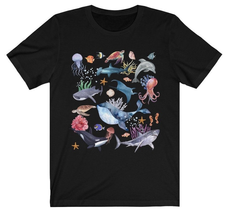 May include: Black t-shirt with a colorful watercolor design of various sea creatures, including a whale, shark, octopus, sea turtle, and starfish.