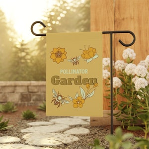 May include: A yellow garden flag with a brown bee and flowers. The flag reads "Pollinator Garden".