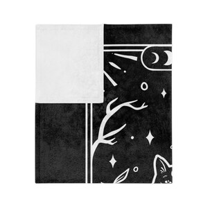 May include: Black and white throw blanket with a celestial design featuring a crescent moon, stars, and a stylized tree with branches. The design is framed by a white border.