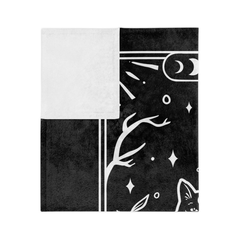 May include: Black and white throw blanket with a celestial design featuring a crescent moon, stars, and a stylized tree with branches. The design is framed by a white border.
