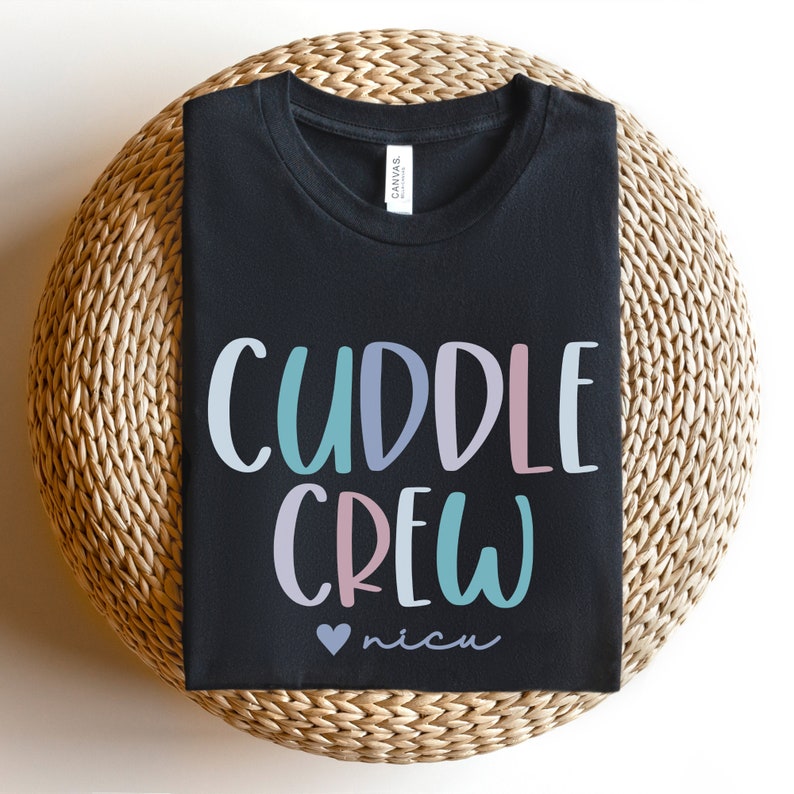 May include: Black t-shirt with the text "Cuddle Crew" in colorful letters and a pink heart with the word "nicu" underneath.