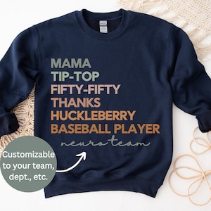 May include: Navy blue sweatshirt with the text "MAMA TIP-TOP FIFTY-FIFTY THANKS HUCKLEBERRY BASEBALL PLAYER neuroteam" in various shades of brown, green, and pink. The text is customizable to your team, department, etc.