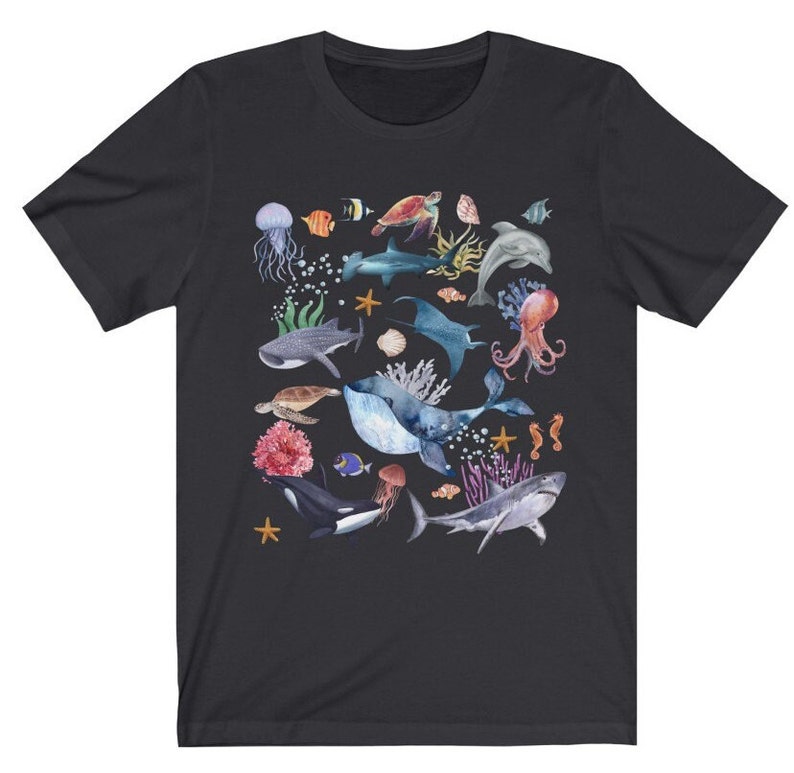 May include: A black t-shirt with a colorful watercolor design of various sea creatures, including a whale, a shark, a jellyfish, a sea turtle, and a starfish.