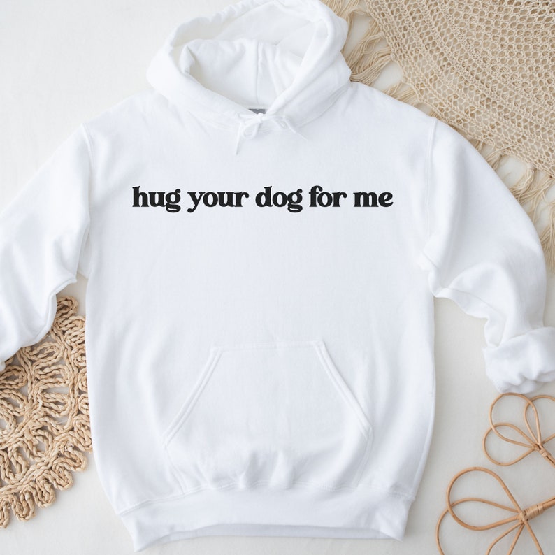 Pu&ograve; includere: Felpa con cappuccio bianca con una stampa nera che dice "hug your dog for me".